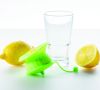 Zitronenpresse in grün mit zwei Zitronen und einem Wasserglas.