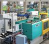 Ein Roboter übergibt die Bauteile von der Spritzgießmaschine an die CNC-Bearbeitung.