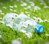 Plastic bottle on grass with recycle logo