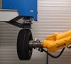 Eine Laseranlage mit gelben Roboter-Arm fertigt einen schwarzen Reifenprototypen.